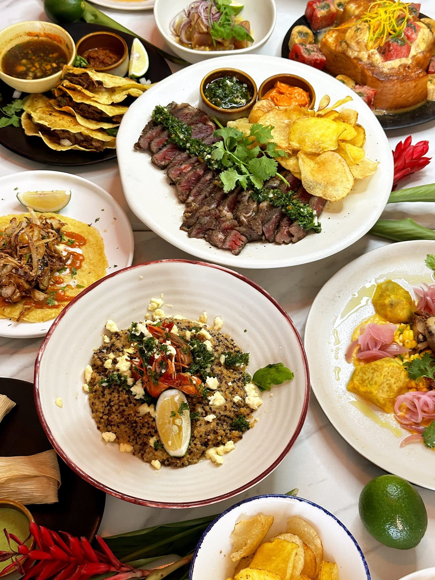 Overhead spread of Latin American dishes for group dining at Muchos Boracay, including grilled steak with chimichurri, tacos, ceviche, and a shrimp quinoa bowl